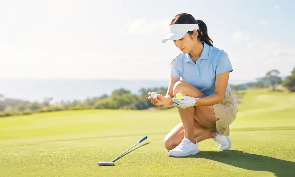 女性ゴルファーが2種類のゴルフボールをグリーン周りで打ち比べるイメージ